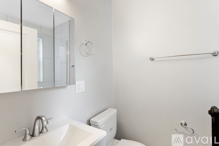 A bathroom with a white sink, toilet, and a mirror.