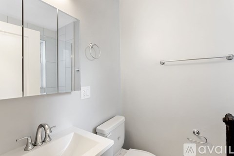 A bathroom with a white sink, toilet, and a mirror.