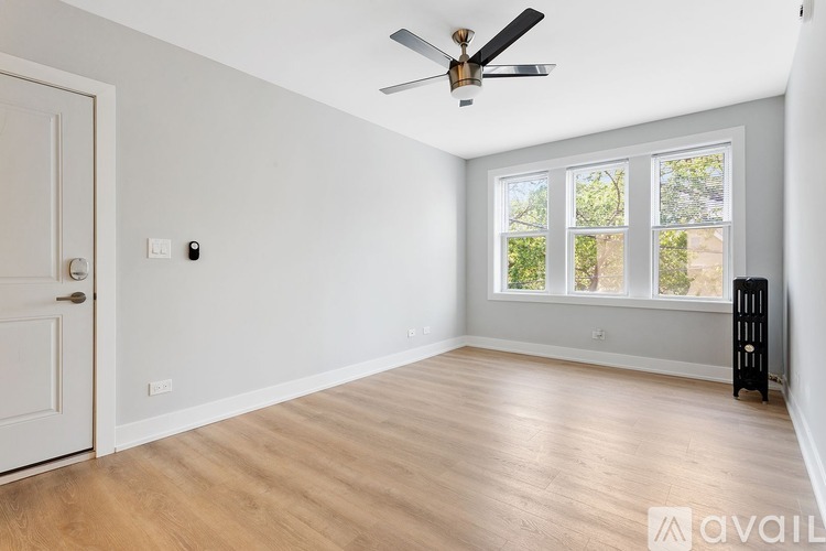 A room with a ceiling fan and a window with a view of trees.