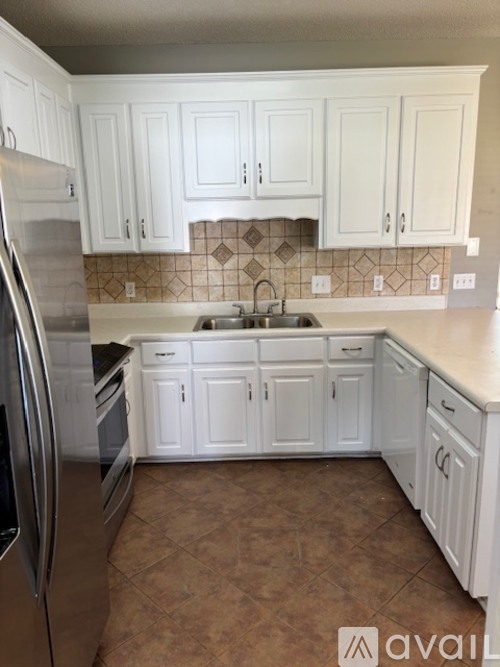 A kitchen with white cabinets and a stainless steel refrigerator.