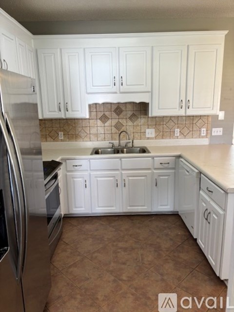 A kitchen with white cabinets and a stainless steel refrigerator.