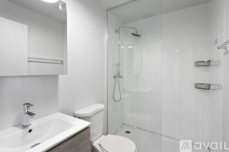 A white bathroom with a sink, toilet, and shower.