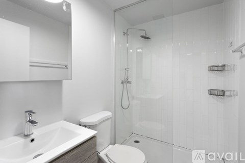 A white bathroom with a sink, toilet, and shower.