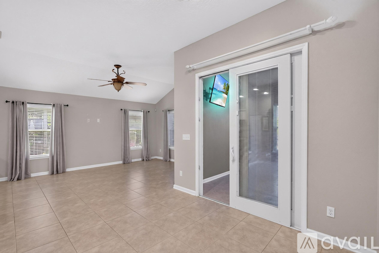 A spacious room with a ceiling fan and sliding glass doors.