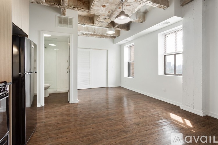 A spacious room with wooden floors and exposed ceiling beams.