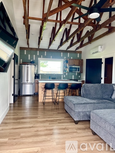 A kitchen with a refrigerator, a microwave, and a bar area with chairs.