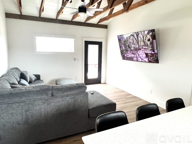 A living room with a grey couch, a television, and a wooden floor.