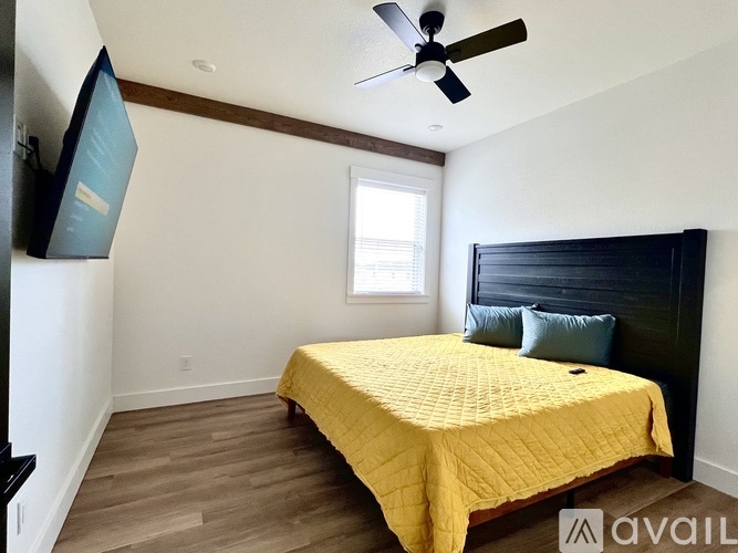 A bedroom with a bed, a ceiling fan, and a window.