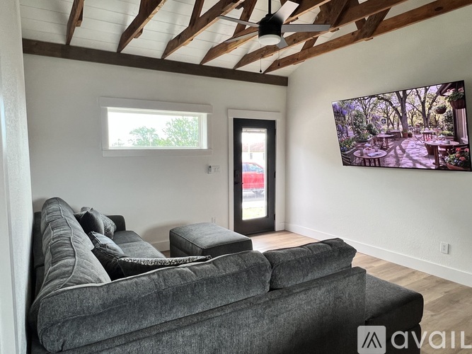 A living room with a grey couch and a flat screen TV mounted on the wall.