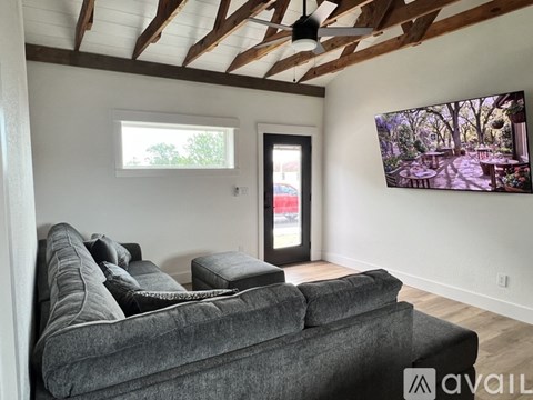 A living room with a grey couch and a flat screen TV mounted on the wall.