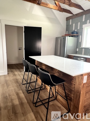 A kitchen with a white counter and black chairs.