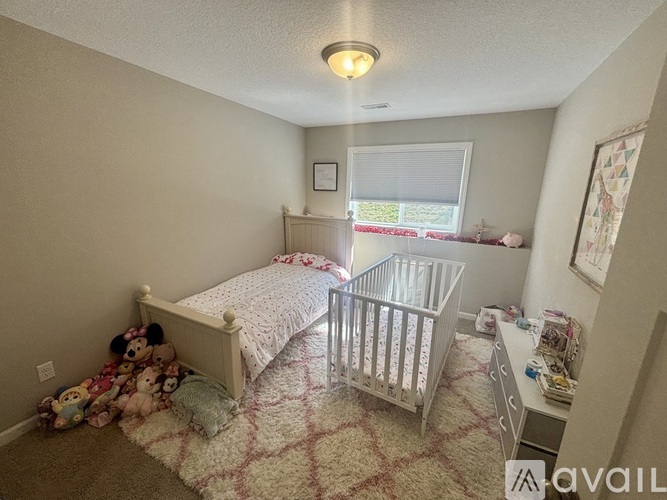 A bedroom with a white bed and a baby crib.