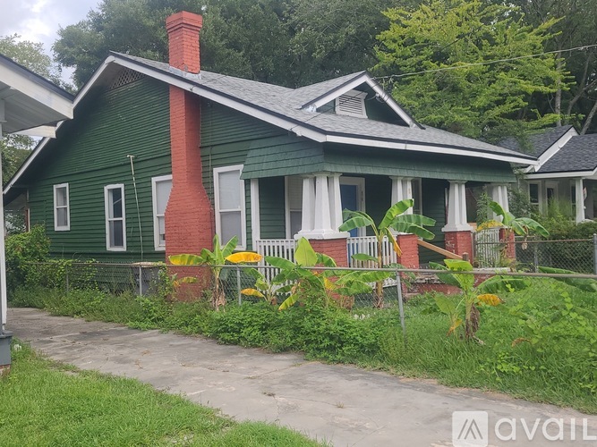 A green house with a red chimney is for sale.