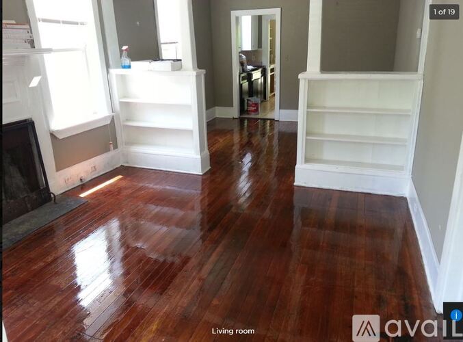 A living room with wood flooring and white bookshelves.