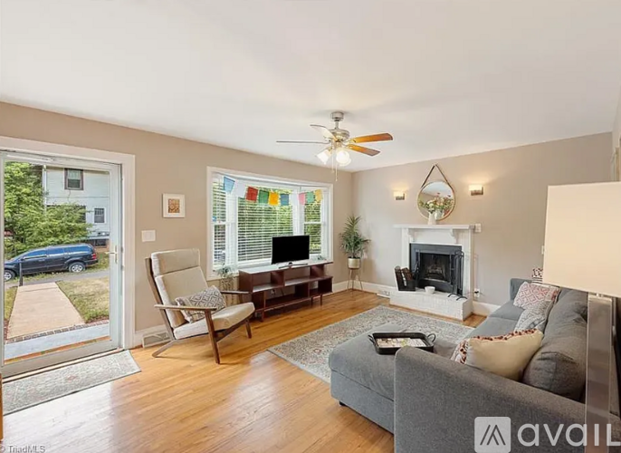 A living room with a grey couch, a chair, a fireplace, and a ceiling fan.