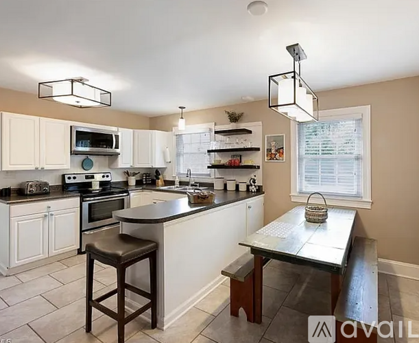 A kitchen with a table and stool in front of it.