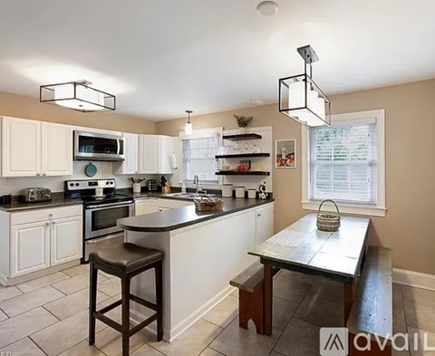 A kitchen with a table and stool in front of it.