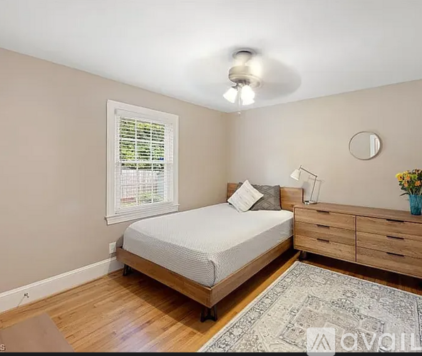 A bedroom with a bed, dresser, and window.