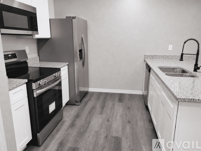 A kitchen with a black stove top oven, a black microwave, a black refrigerator, and a granite countertop.