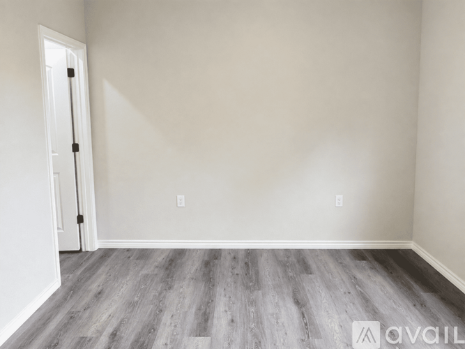 A room with a wooden floor and a door on the left side.