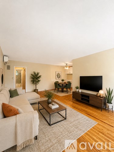 A living room with a white couch, a coffee table, and a television.