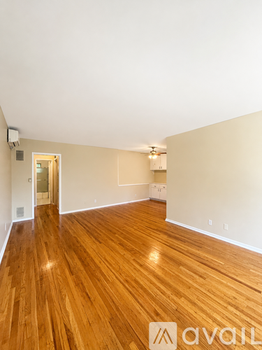 A room with wooden flooring and a doorway leading to another room.