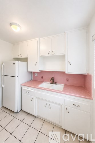 A kitchen with white cabinets and a pink counter.