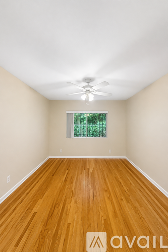 A room with wooden floors and a window with a view of trees.