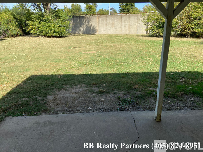 A grassy area with a concrete slab and a pole in the foreground.