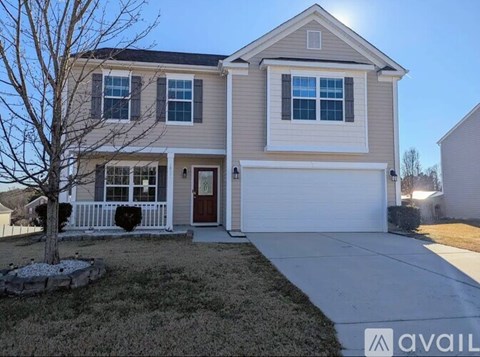 A two-story house with a garage and a tree in front.