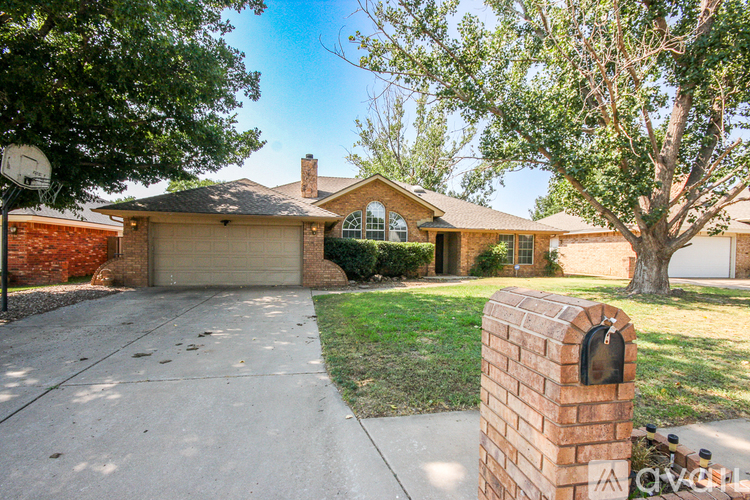A house with a driveway and a brick pillar in front.
