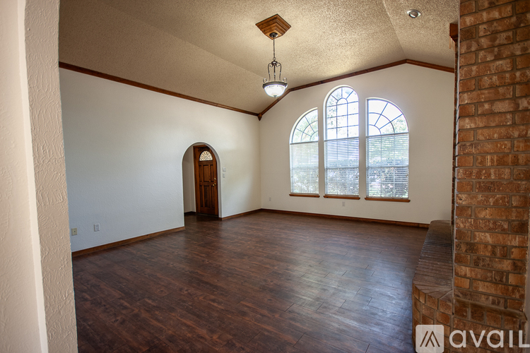 A room with wooden floors and a brick column.