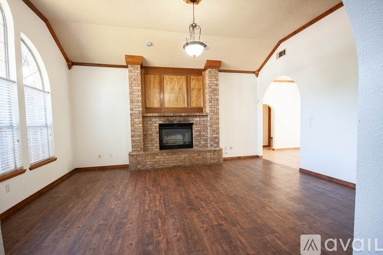 A large empty room with a fireplace and wooden floors.