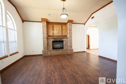 A large empty room with a fireplace and wooden floors.