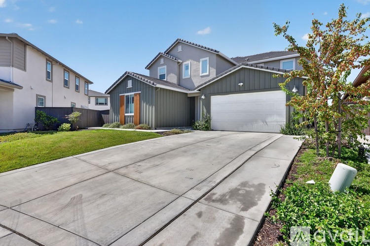 A modern house with a grey garage door and a driveway.