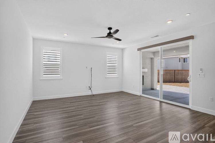A spacious room with wooden flooring and a ceiling fan.