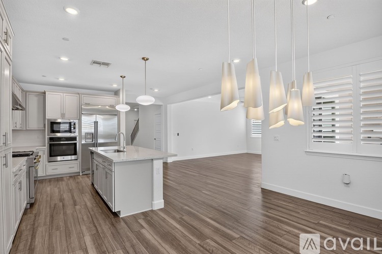 A modern kitchen with white cabinets and a wooden floor.