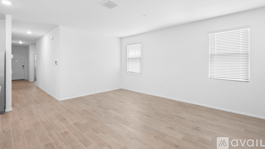 A spacious room with wooden flooring and white walls.