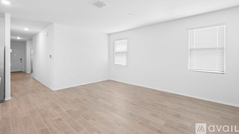 A spacious room with wooden flooring and white walls.