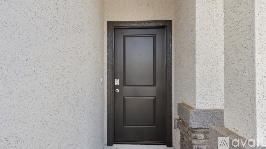 A black door with a silver handle is set in a white wall.
