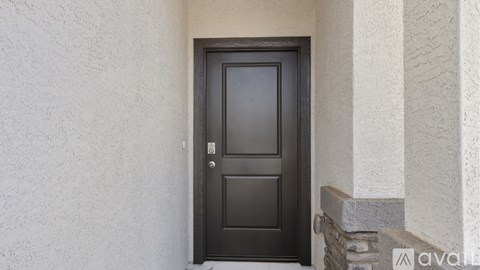 A black door with a silver handle is set in a white wall.