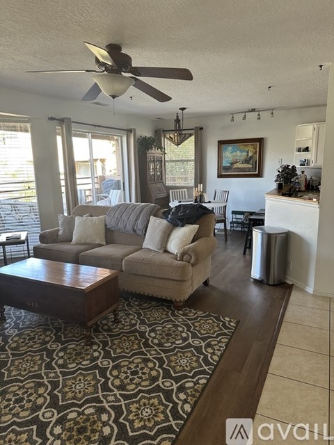 A living room with a couch, a coffee table, and a ceiling fan.