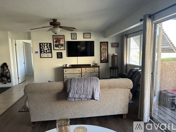 A living room with a couch, a television, and a ceiling fan.