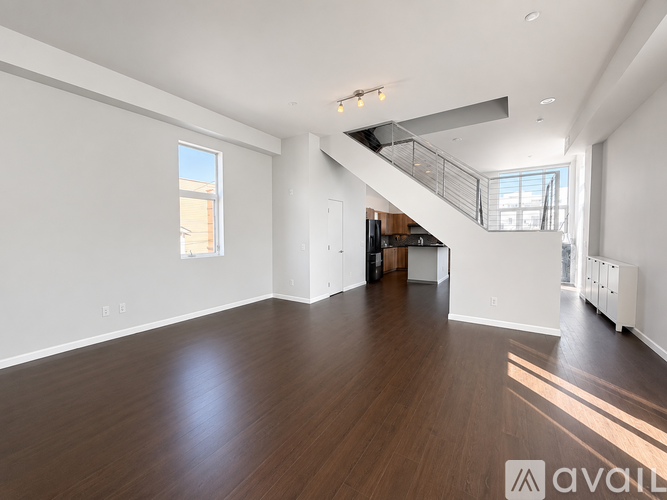 A spacious room with wooden floors and a staircase.