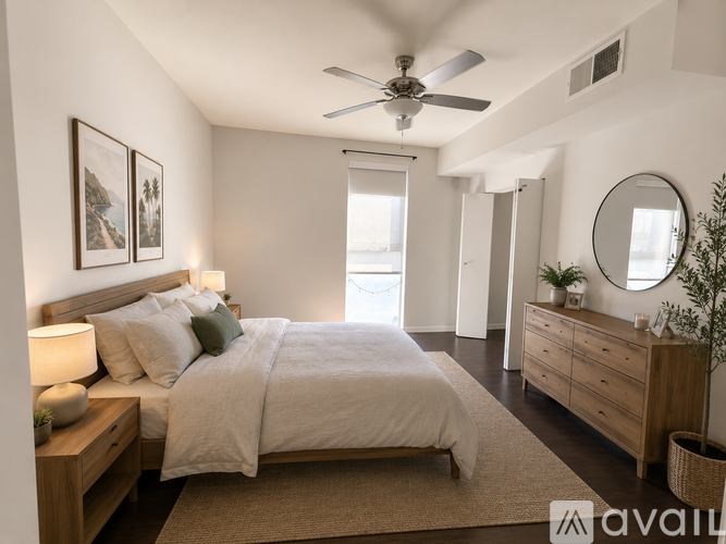 A bedroom with a large bed, a ceiling fan, and a mirror on the wall.