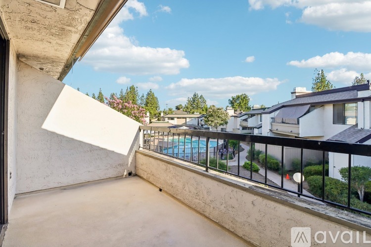 A balcony with a pool in the distance and a fence in the foreground.