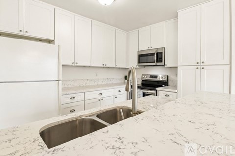 A kitchen with white cabinets and marble countertops.