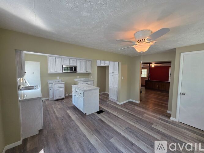 A spacious kitchen with white cabinets and a wooden floor.