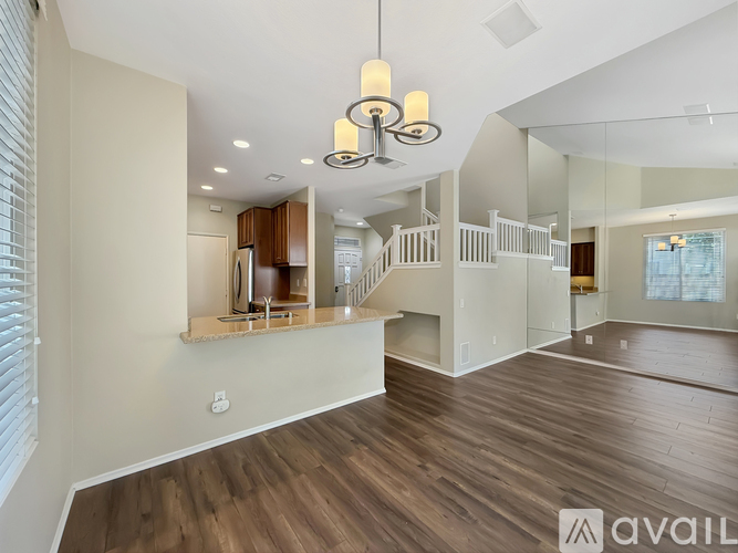 A spacious living room with wooden floors and a large mirror on the wall.