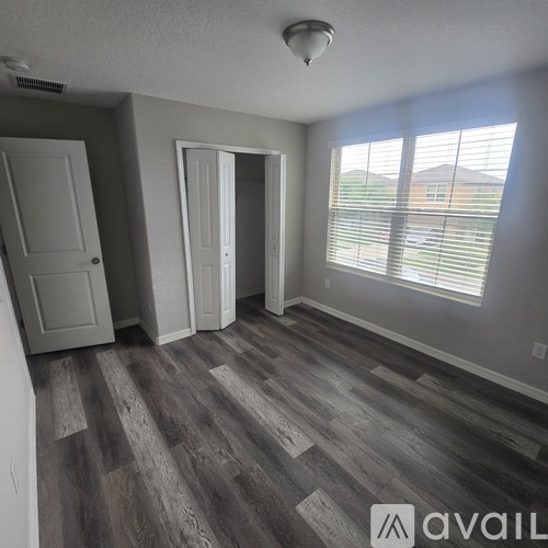 A room with a grey floor and a window with blinds.
